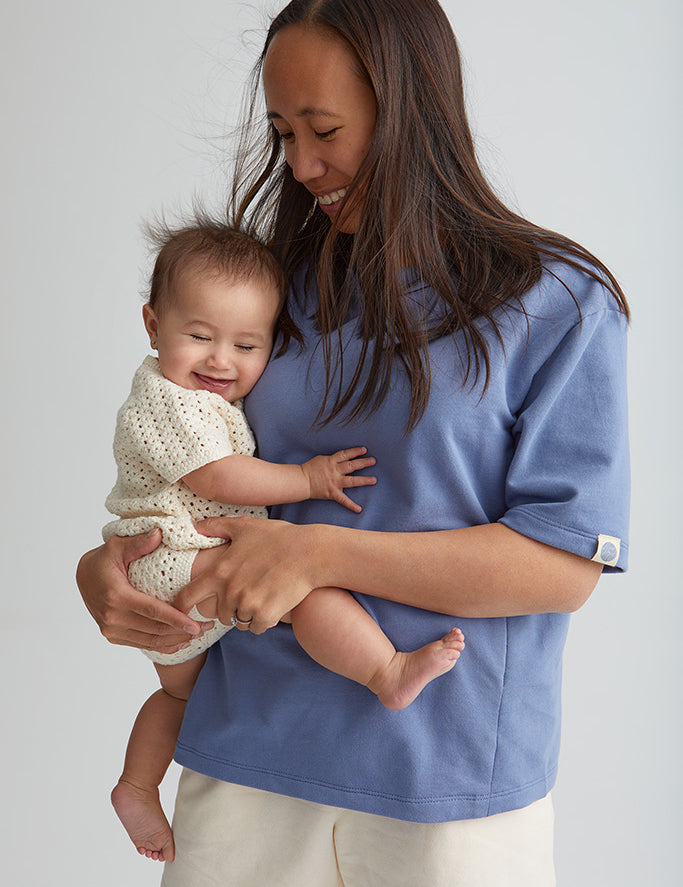 Maman qui tient bébé dans ses bras. Porte le tee-shirt box d'allaitement couleur bleu de mèr(e)
