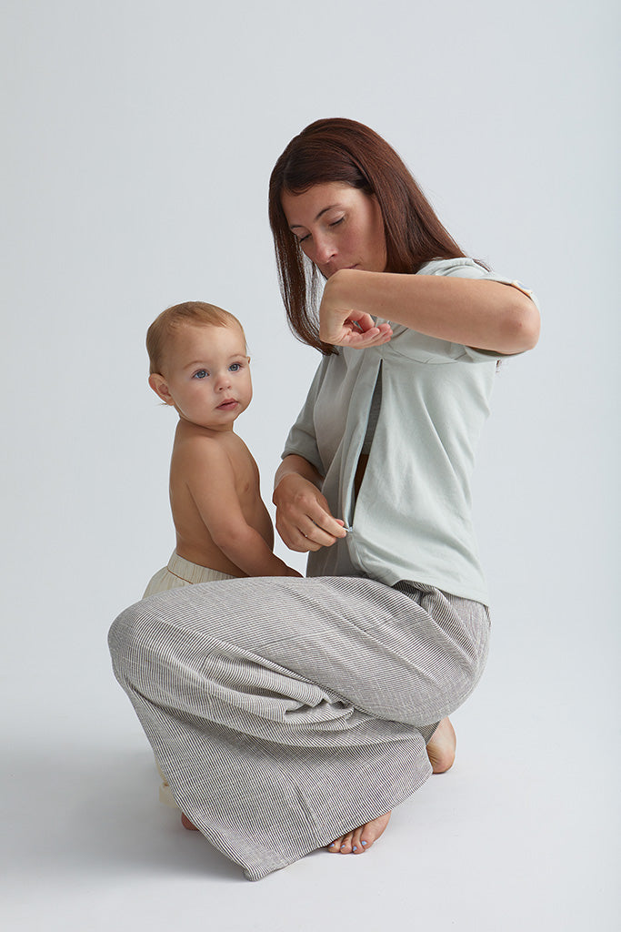 Maman qui ouvre son tee-shirt Box d'allaitement couleur seaglass. S'apprête à allaiter bébé devant elle. 