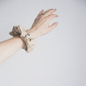 Image d'une main sur fond blanc, chouchou couleur sable doux au poignet.