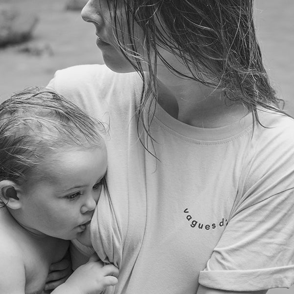 Maman en train d'allaiter sa fille, près d'une cascade dans un tee-shirt d'allaitement vague d'amour avec ouvertures latérales. Cheveux mouillés après une baignade.