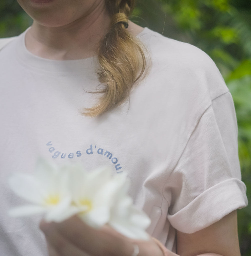 Femme portant le tee shirt Vagues d'amour, avec des fleurs dans ses mains.
