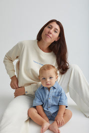 Maman assise avec bébé et qui ouvre zip et qui porte le crewneck d'allaitement Vagues d'amour