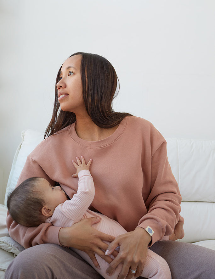 Maman qui allaite bébé assise, porte le crewneck d'allaitement couleur Câlin