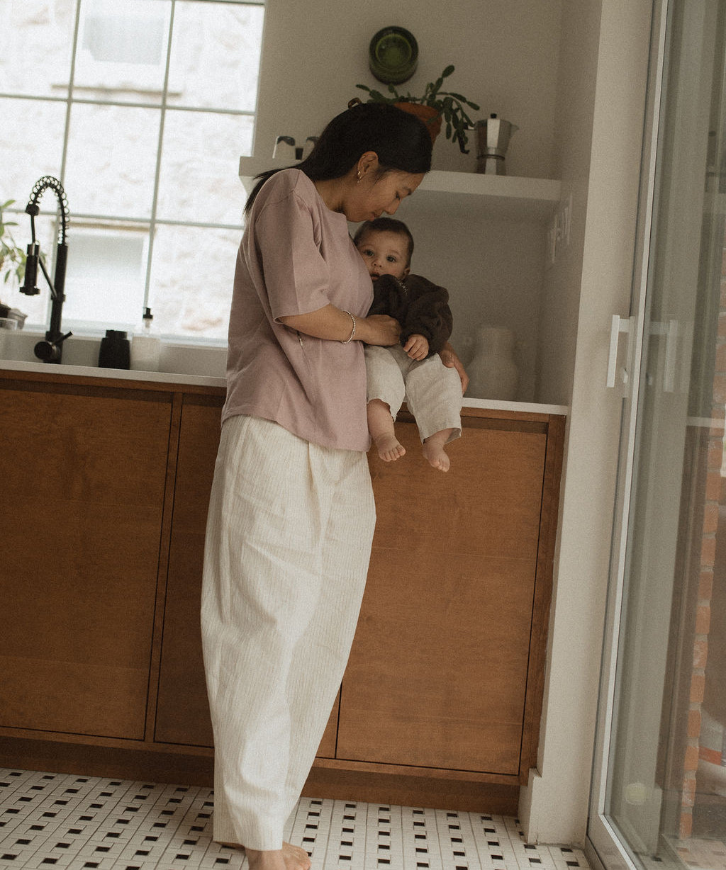 Maman dans la cuisine, avec bébé sur le comptoir, qui va allaiter bébé avec teeshirt d'allaitement Marées couleur Aube