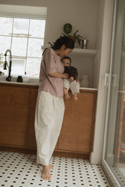 Maman dans la cuisine, avec bébé sur le comptoir, qui va allaiter bébé avec teeshirt d'allaitement Marées couleur Aube