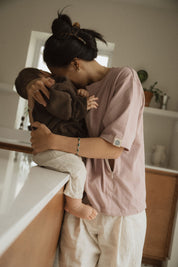 Maman dans la cuisine, avec bébé sur le comptoir, qui va allaiter bébé avec teeshirt d'allaitement Marées couleur Aube