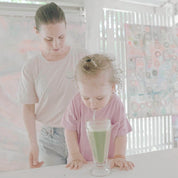 Femme et son enfant qui boit un smoothie dans un café. Maman porte le tee shirt d'allaitement Vagues d'amour.